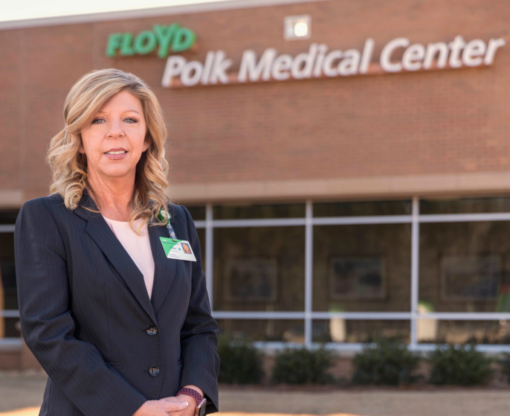 woman standing in front of a brick building that says floyd polk medical center